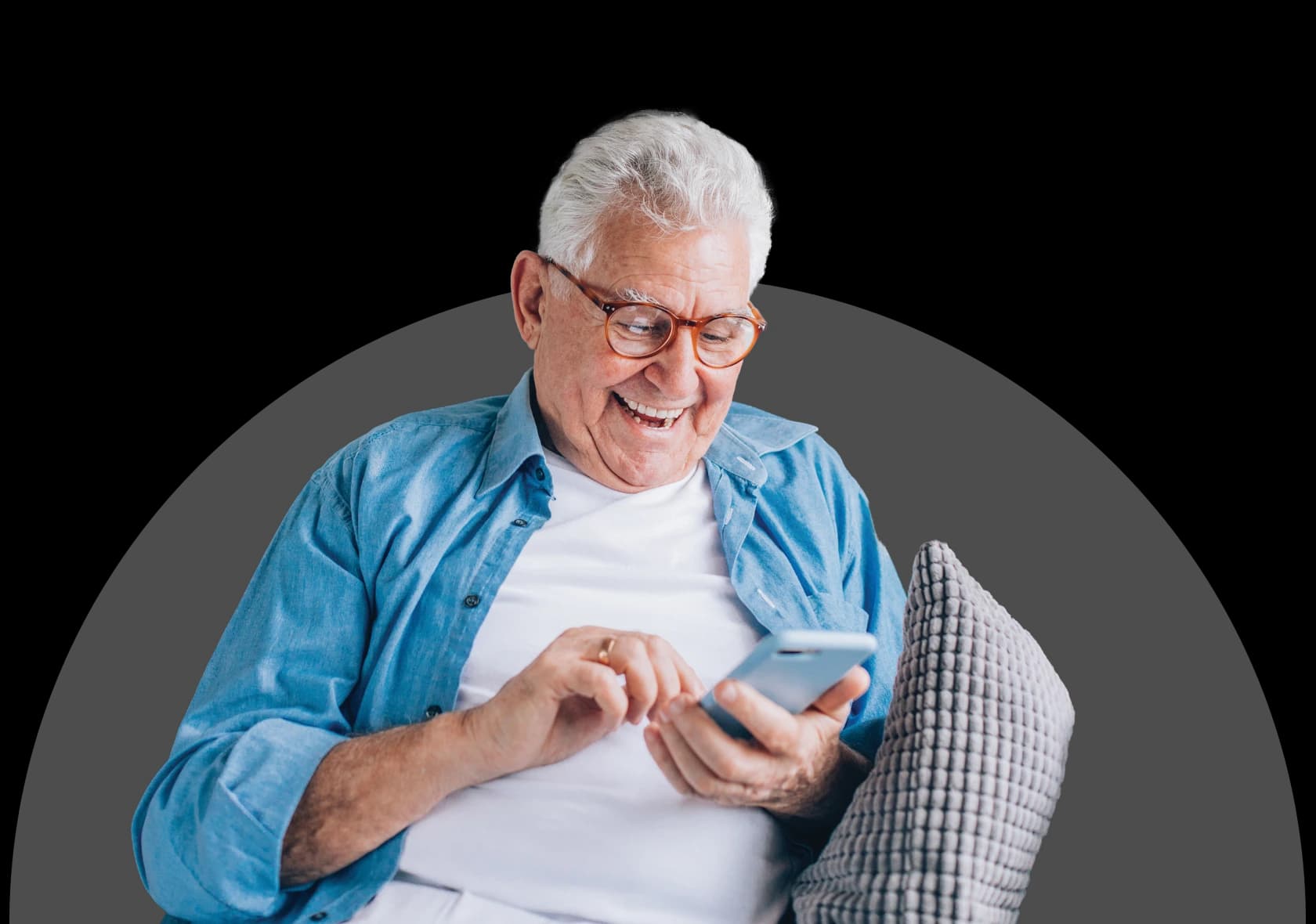 Smiling older man relaxing on a couch using his phone